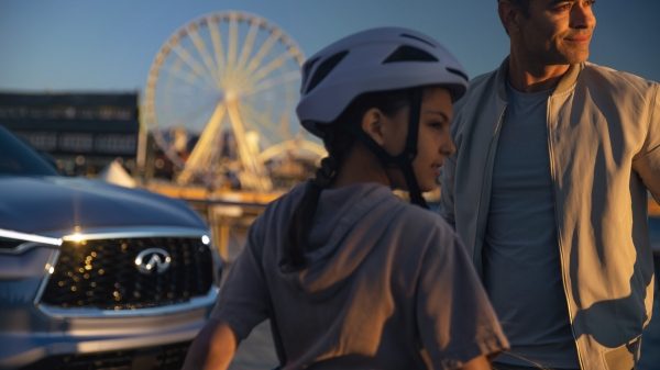INFINITI QX80 owners standing with car in front of ferris wheel