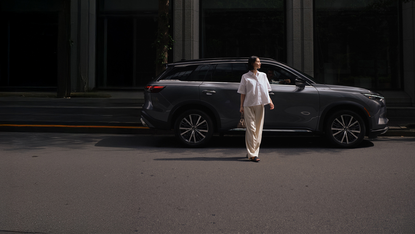 Mujer frente a INFINITI QX60 en una toma lateral