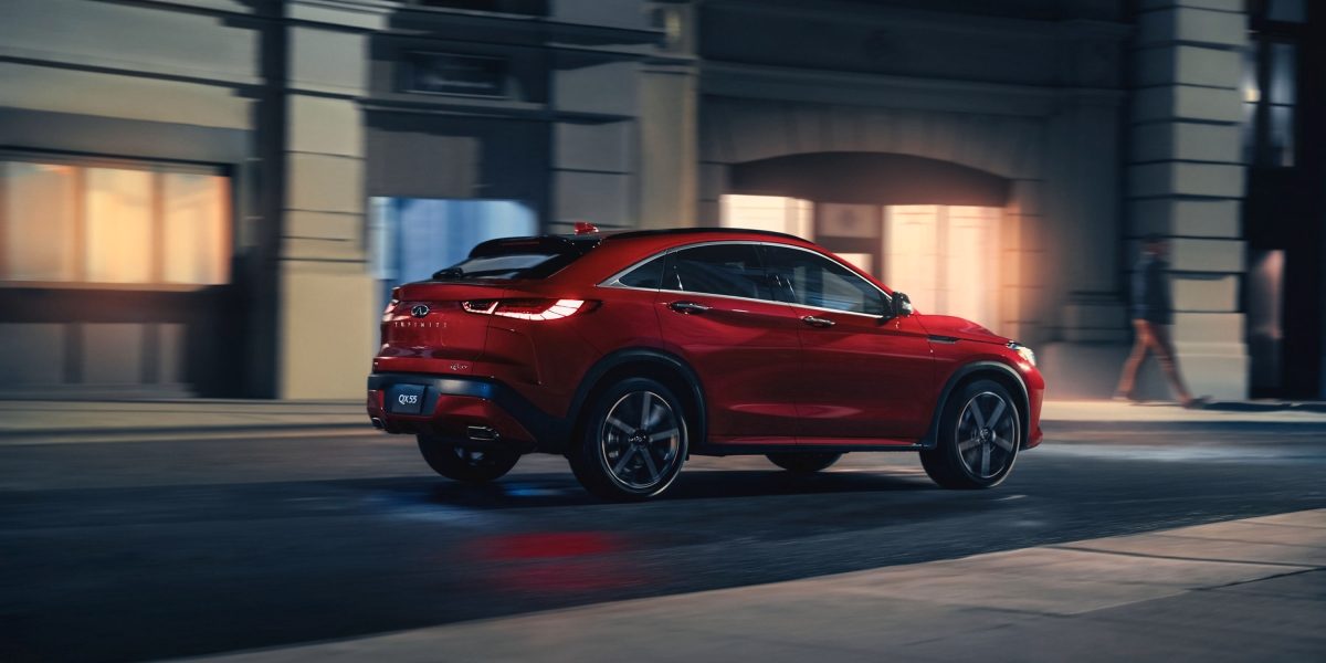 QX55 driving down an urban road at night