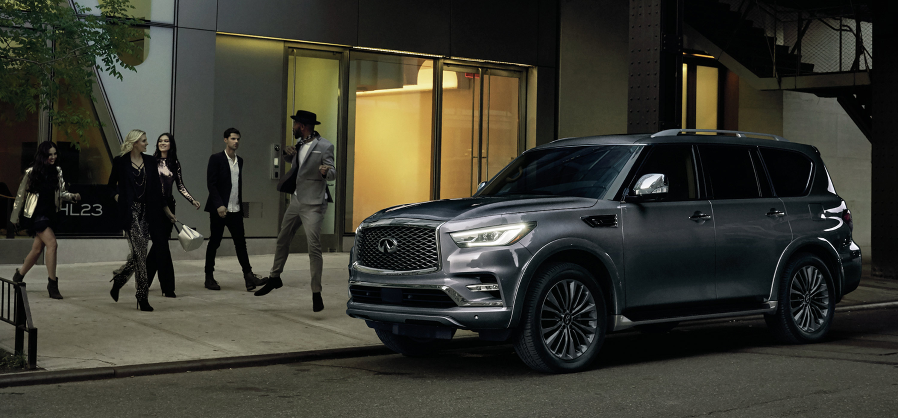 Friends walking to a dark grey 2024 INFINITI QX80 7-8 passenger SUV