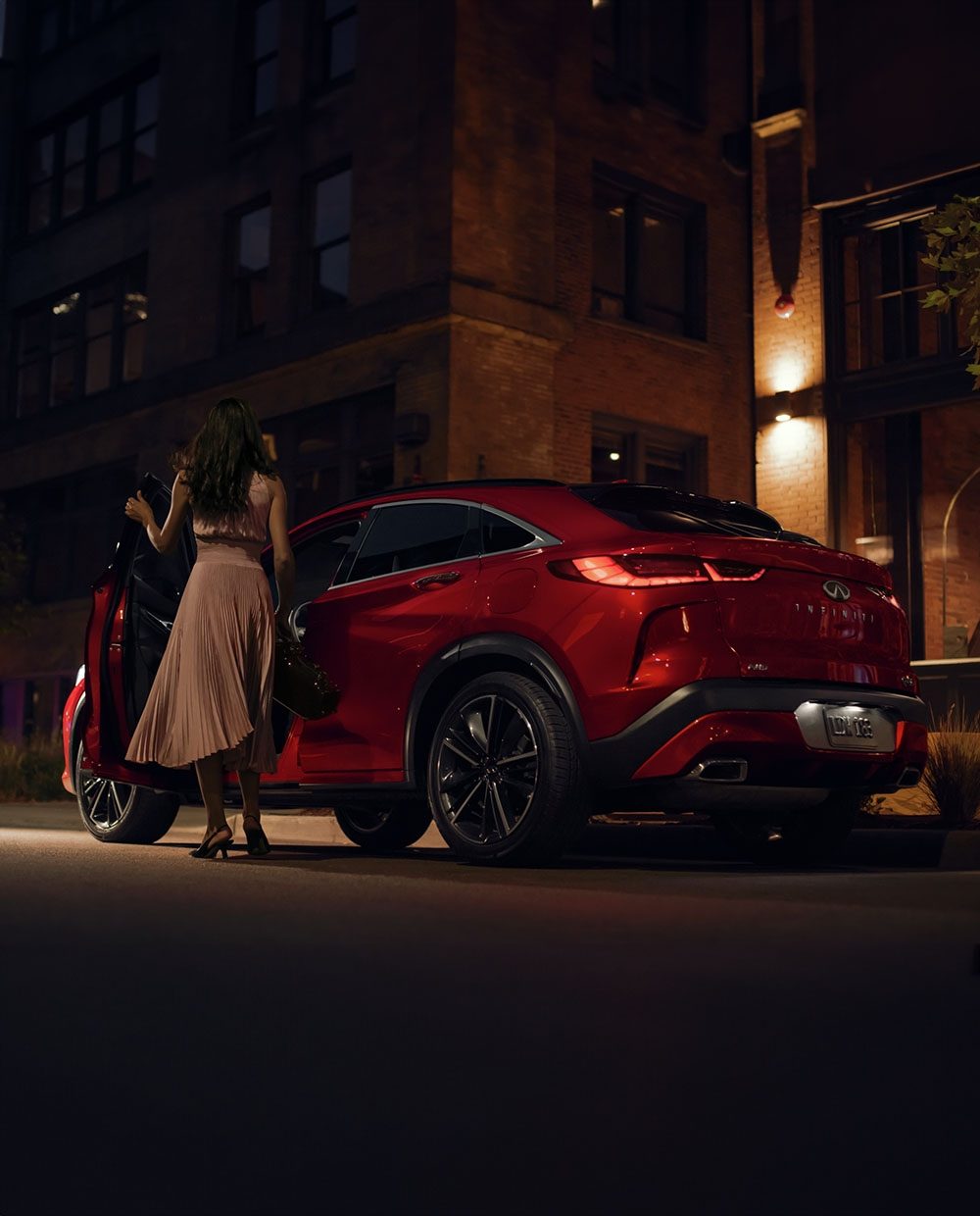 Angled view of a red 2024 INFINITI QX55 crossover SUV at night