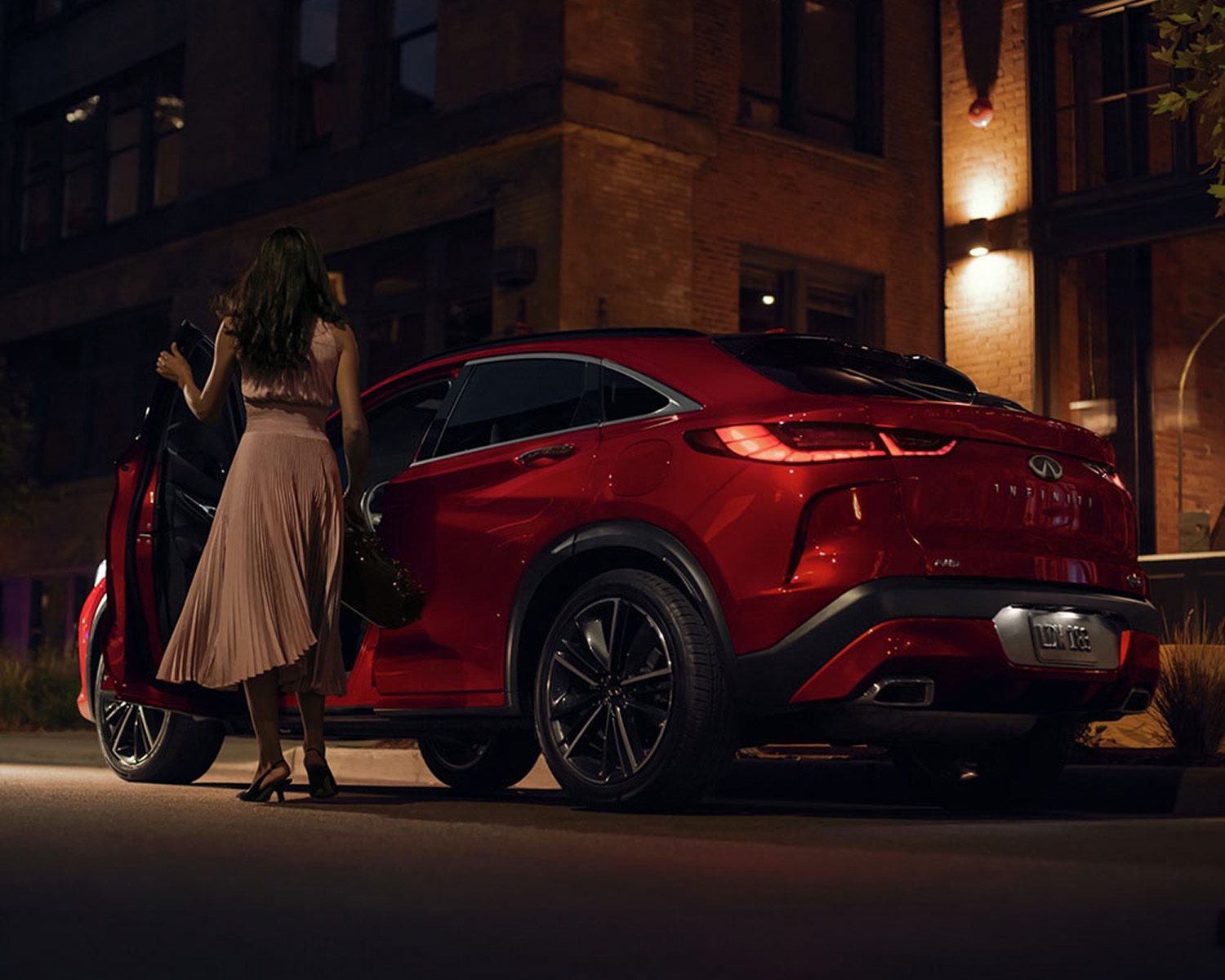Angled view of a red 2024 INFINITI QX55 crossover SUV at night