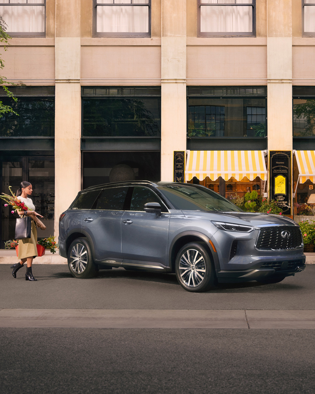 Perfil frontal del INFINITI QX60 estacionado frente a una casa al anochecer