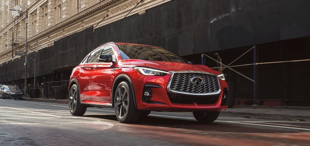 2025 INFINITI QX55 driving past city buildings