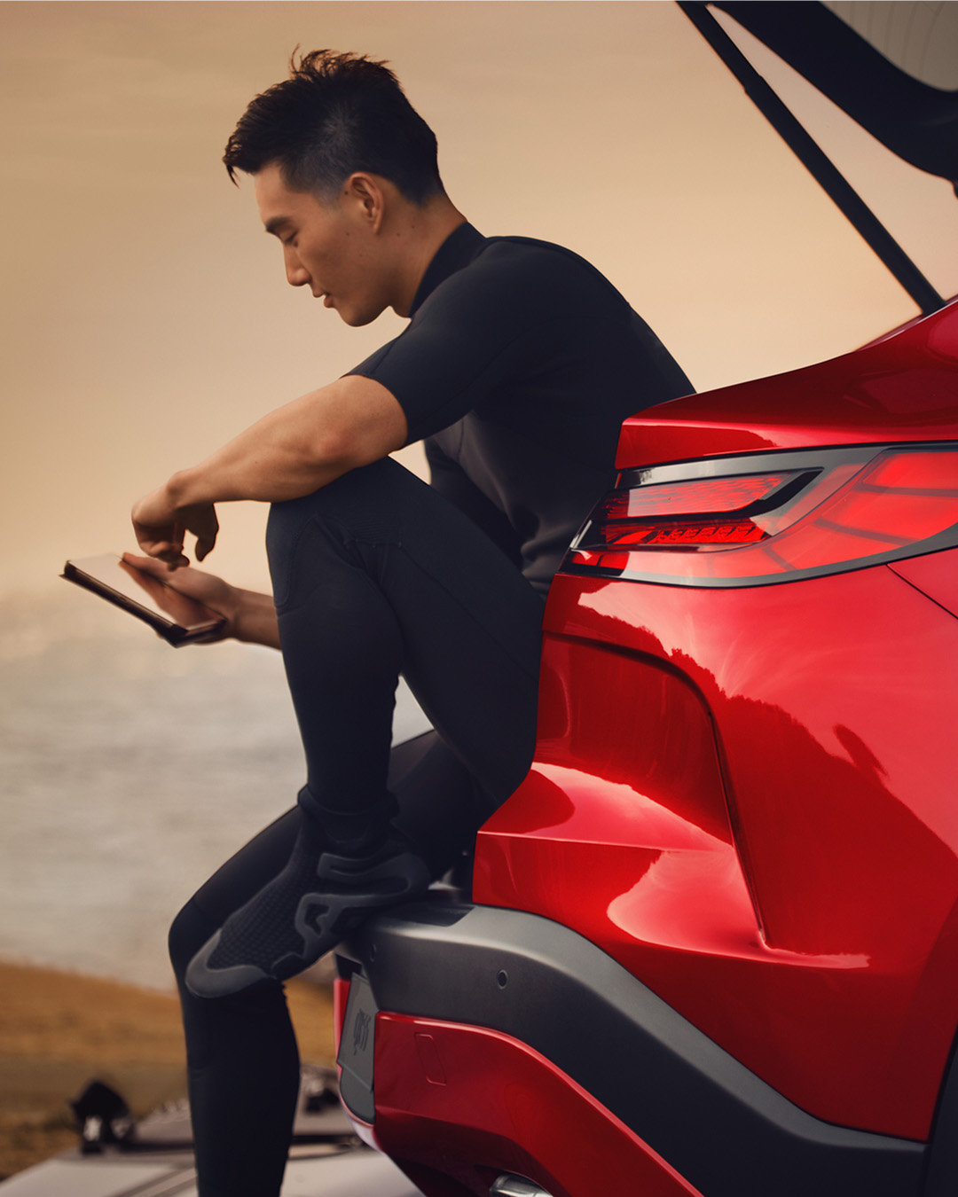 Man sits on QX55 trunk using Wi-Fi hotspot