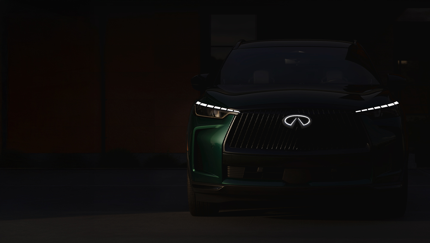 2026 INFINITI QX60 in Deep Emerald Green parked near a theater entrance at dusk, family walking toward building