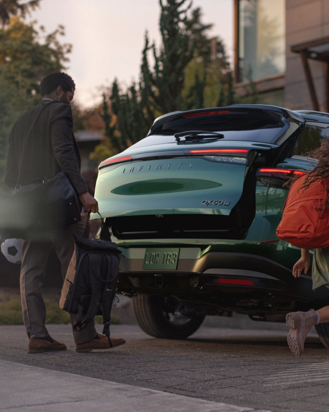 Rear liftgate opening hands-free as man and child approach with gear