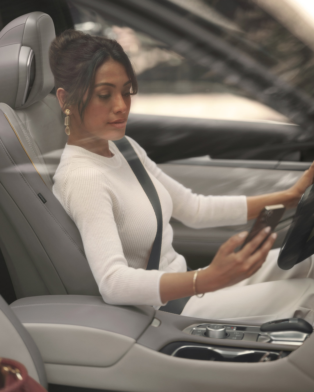 Woman in QX60 front seat using smartphone with InTouch Wi-Fi hotspot active