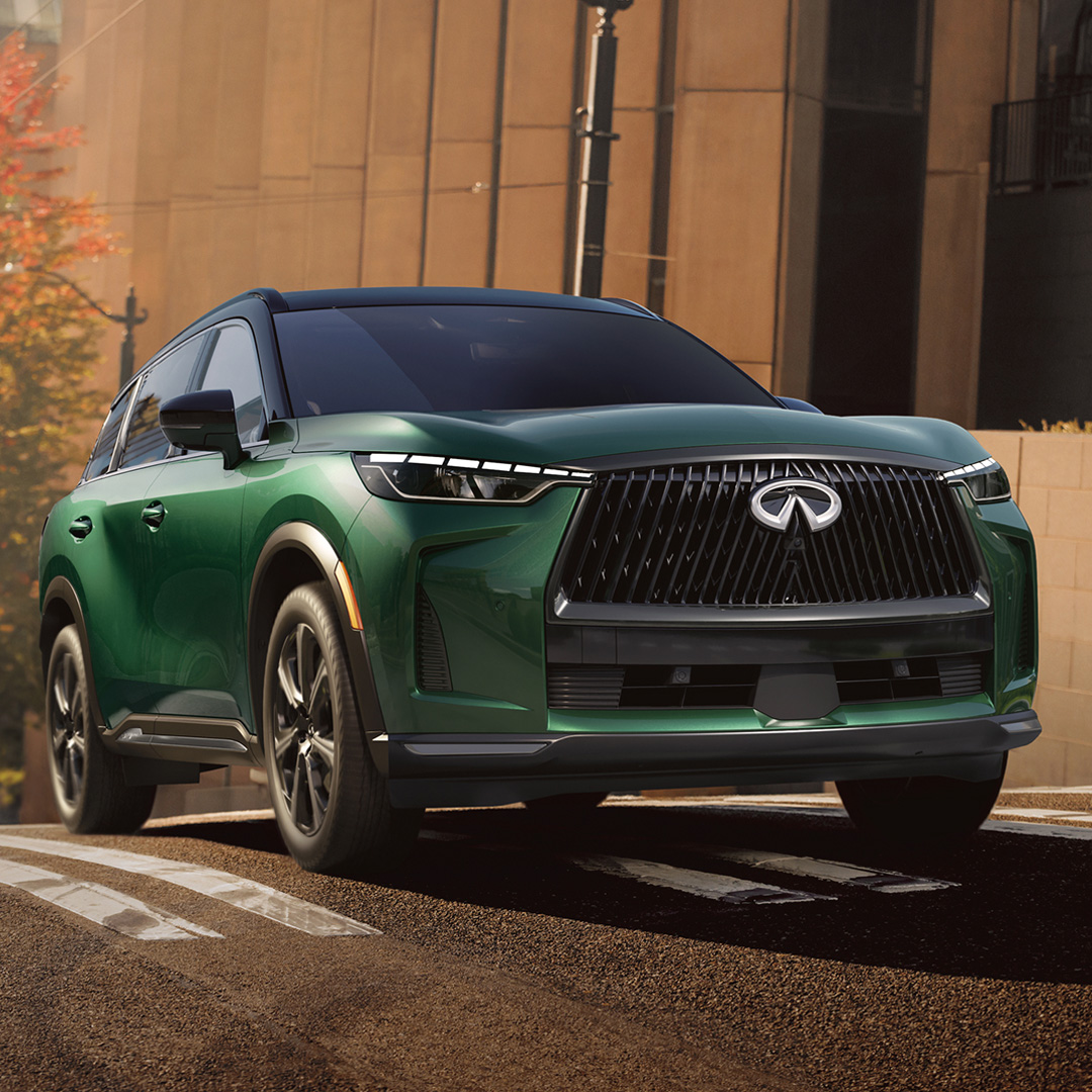 2027 INFINITI QX60 driving through city with high waistline and sculpted body panels