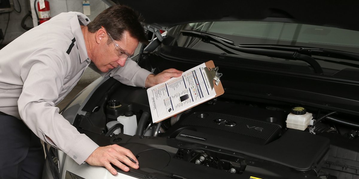 A male INFINITI technician inspecting an engine