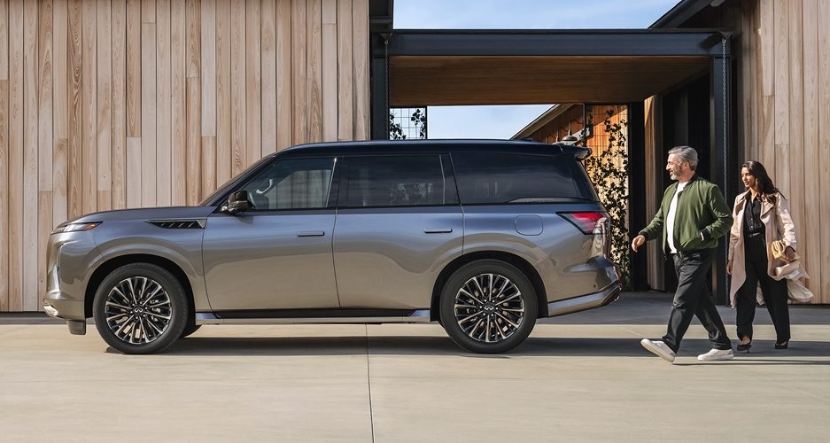 INFINITI QX80 luxury SUV parked outside a modern home with couple walking nearby