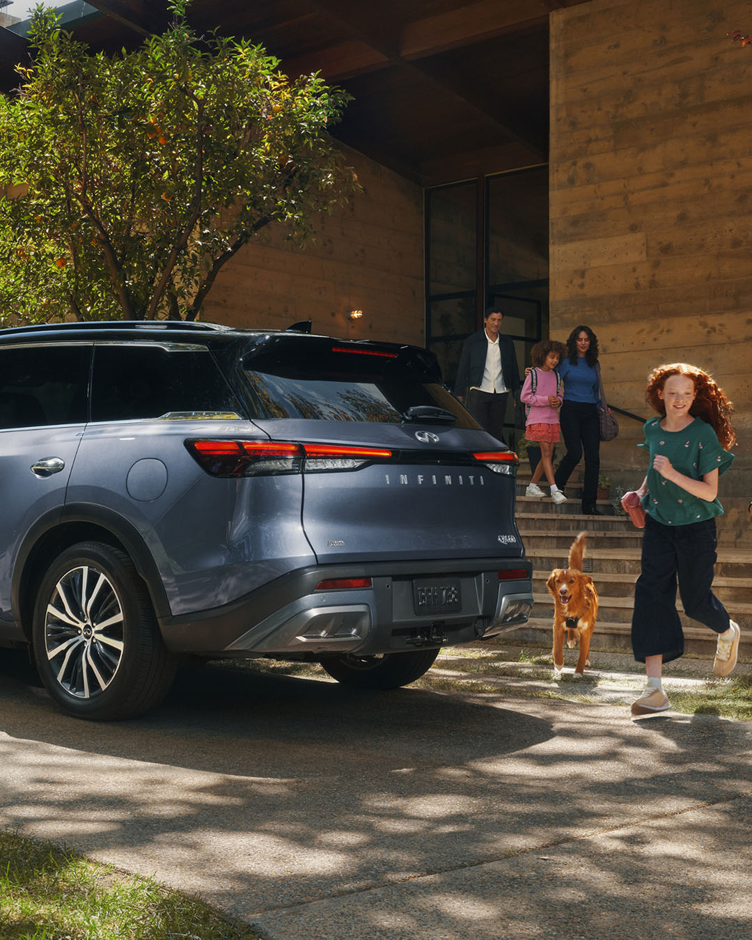SUV INFINITI estacionado afuera de una casa con una familia y su perro cerca, mostrando la versatilidad del vehículo