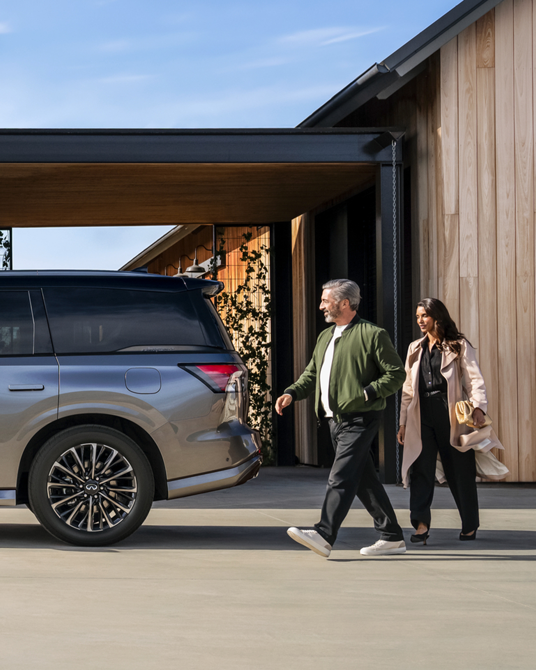 SUV INFINITI estacionado afuera de una casa con una familia y su perro cerca, mostrando la versatilidad del vehículo