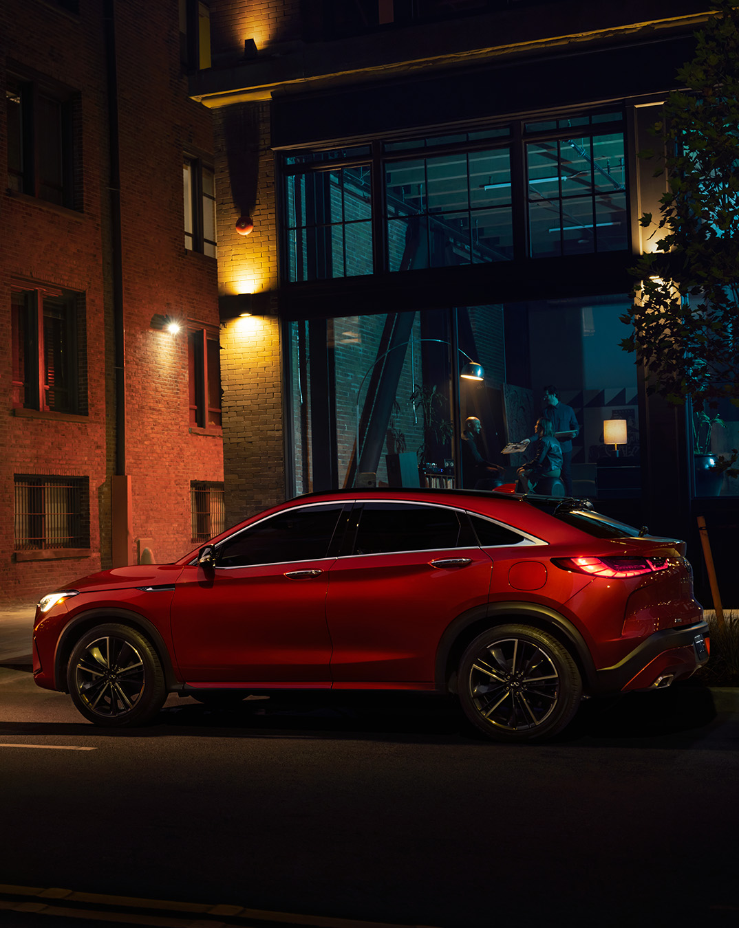 Red INFINITI QX55 parked in front of brick building