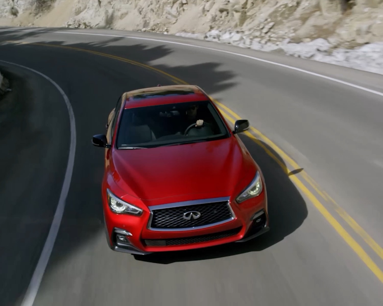 Q50 Red Sport edition speeding through mountain curve