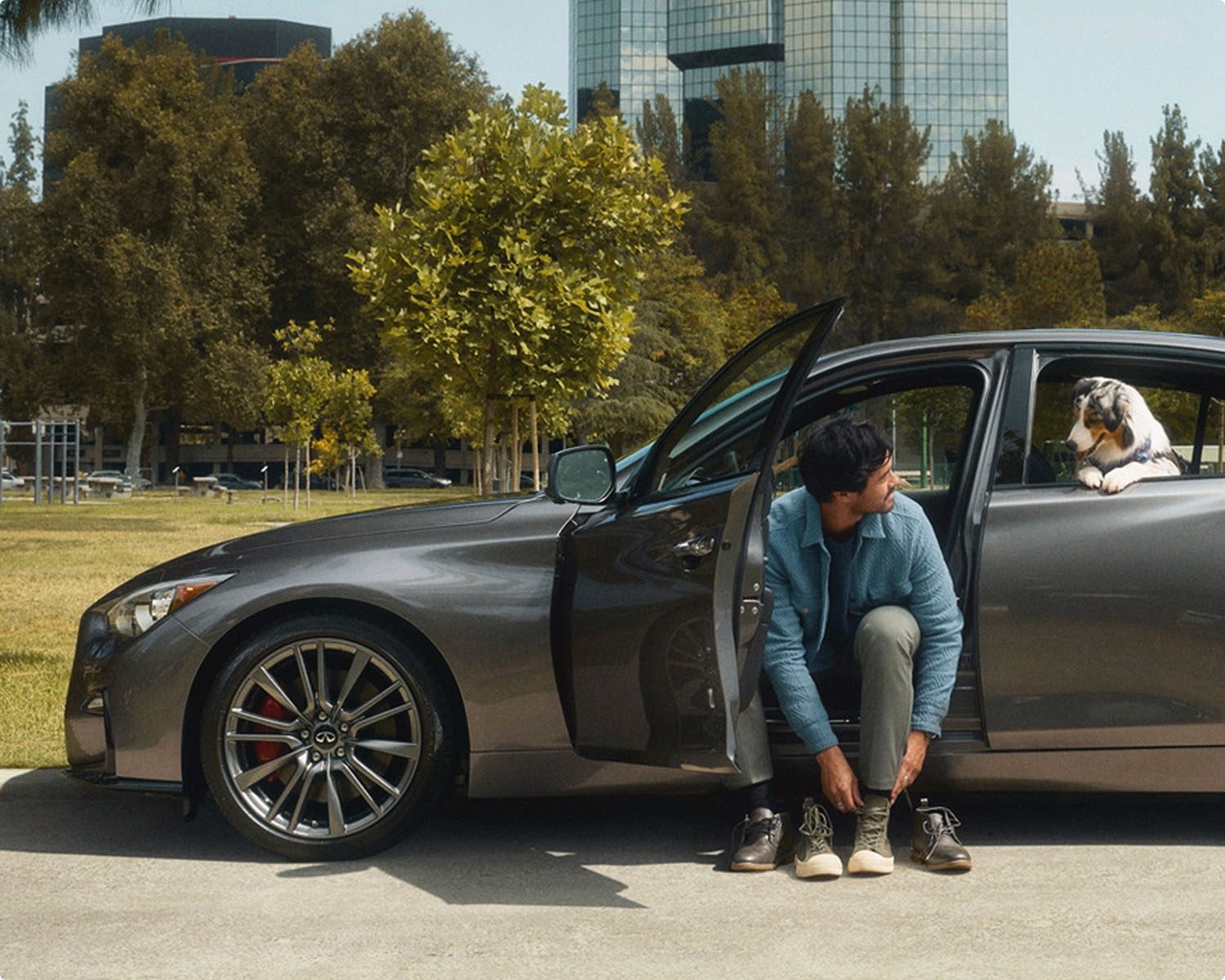 Man sitting in certified pre-owned Q50 with dog