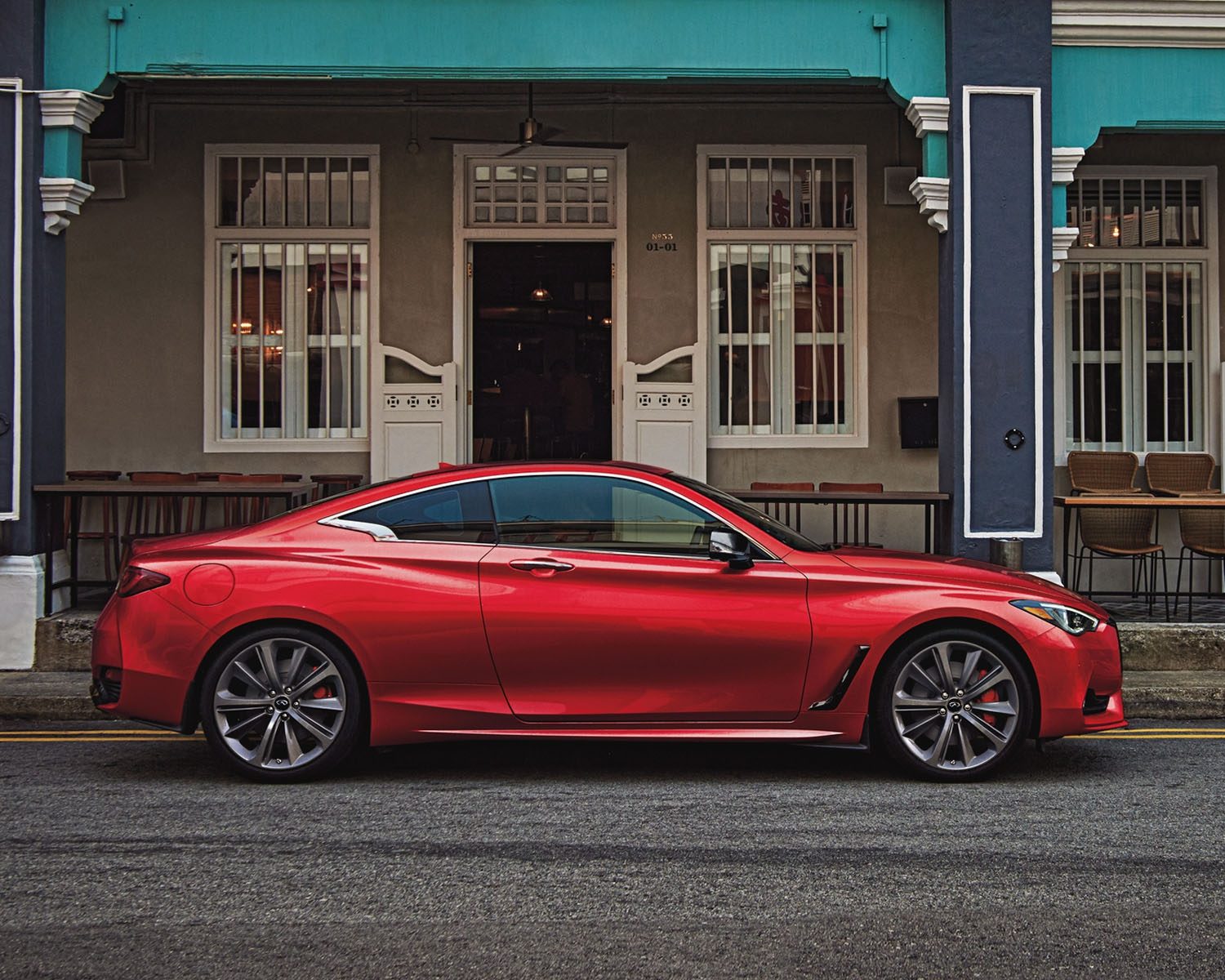 Red Q60 coupe parked in front of colorful urban building