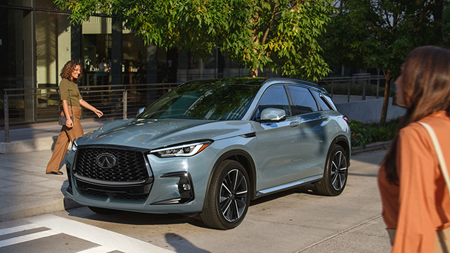 Conductor caminando hacia la SUV compacta INFINITI QX50