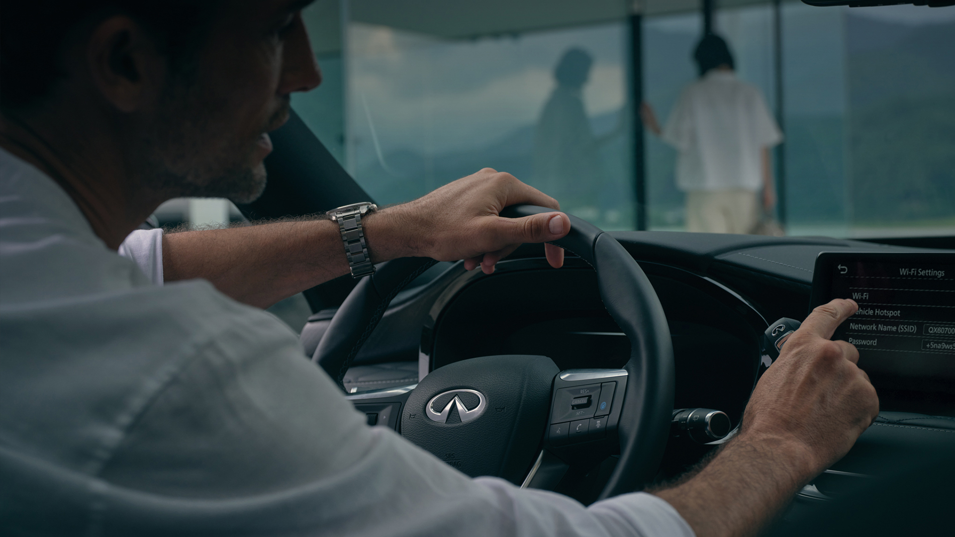 Hombre en su QX55 configurando su sistema de infoentretenimiento