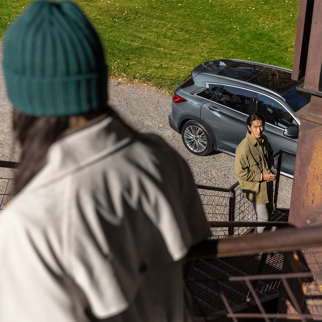 Hombre frente a su QX50, observando a una mujer 