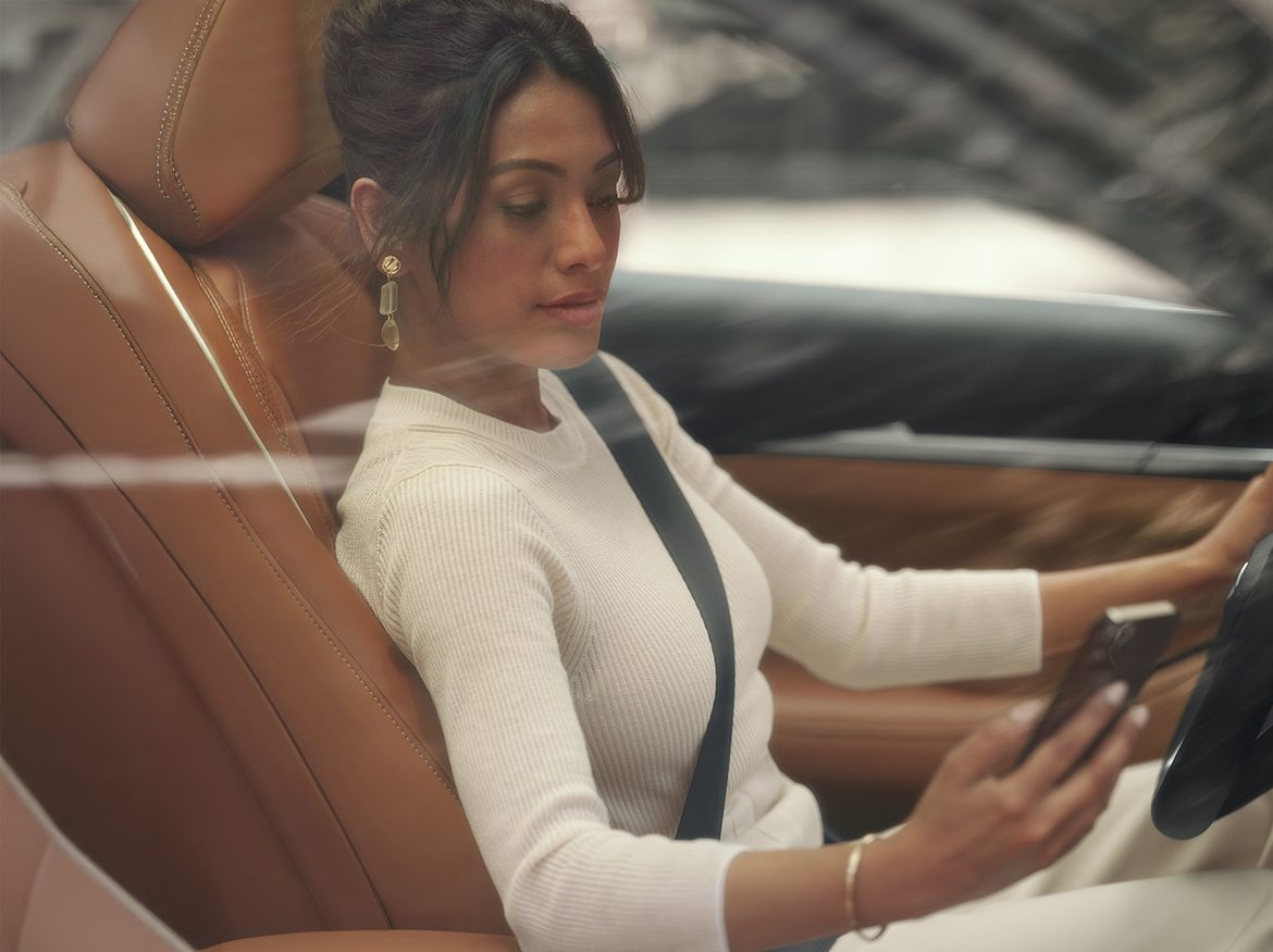 Mujer viendo su celular con la información de su QX60