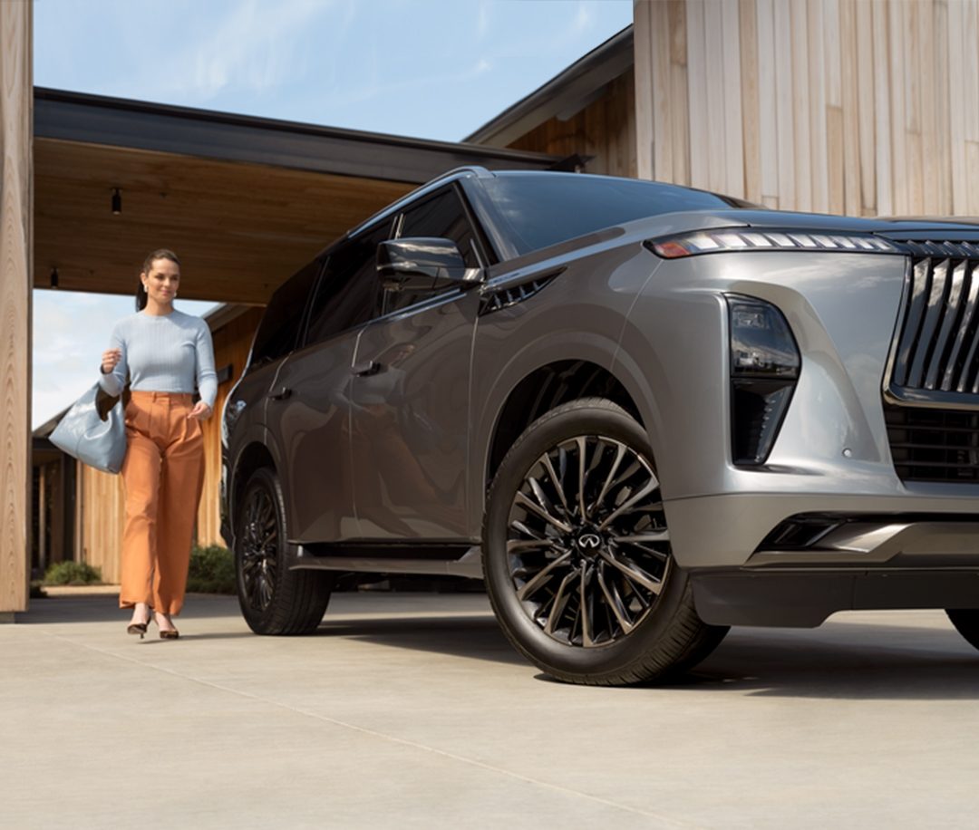 Mujer caminando a un lado de su QX80