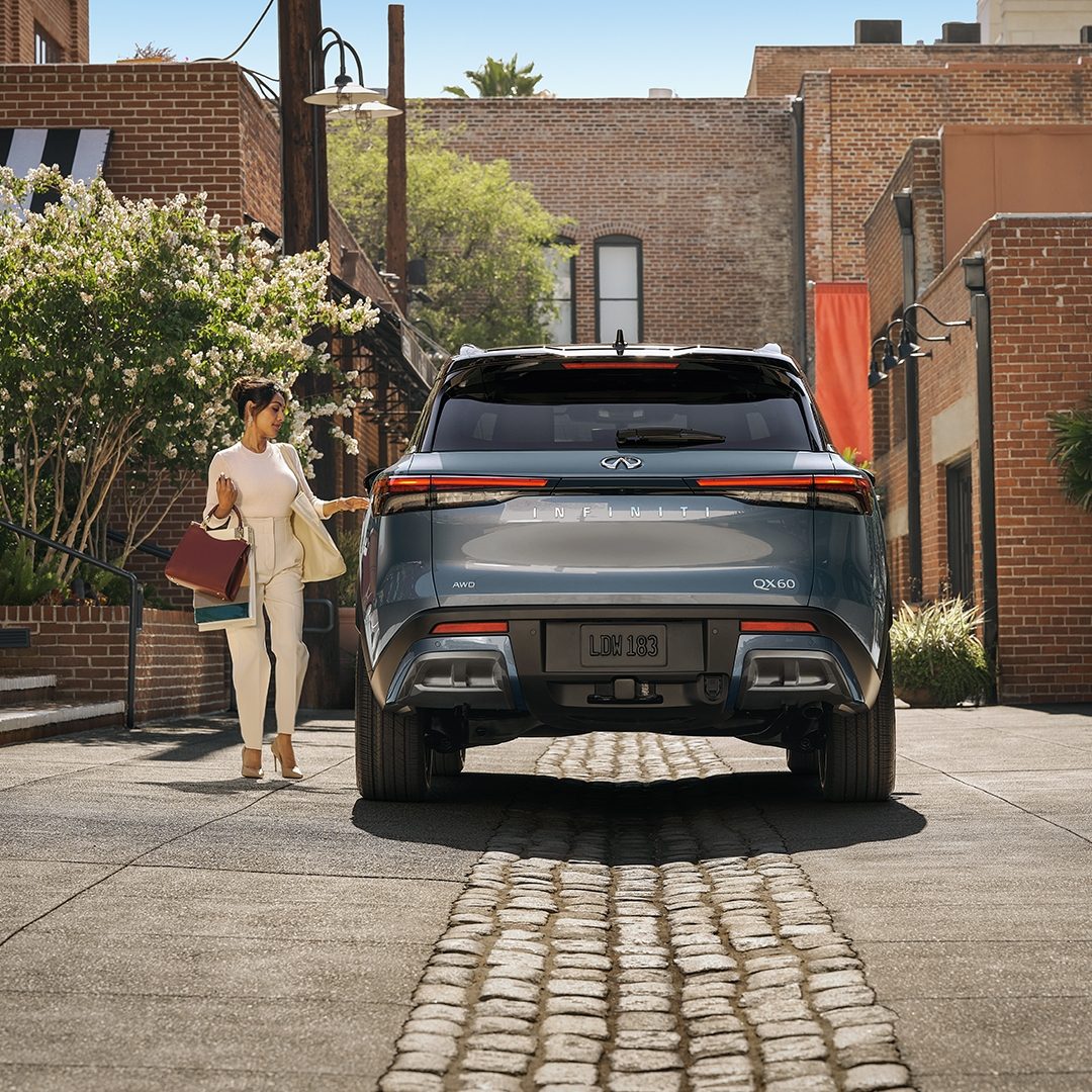 Mujer caminando a un lado de una INFINITI QX60