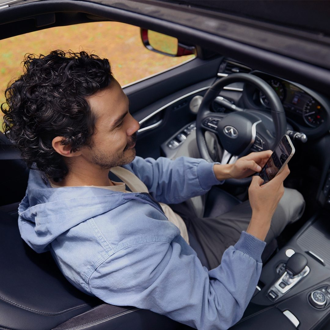 Hombre dentro de su QX55 utilizando la aplicación MiINFINITI App