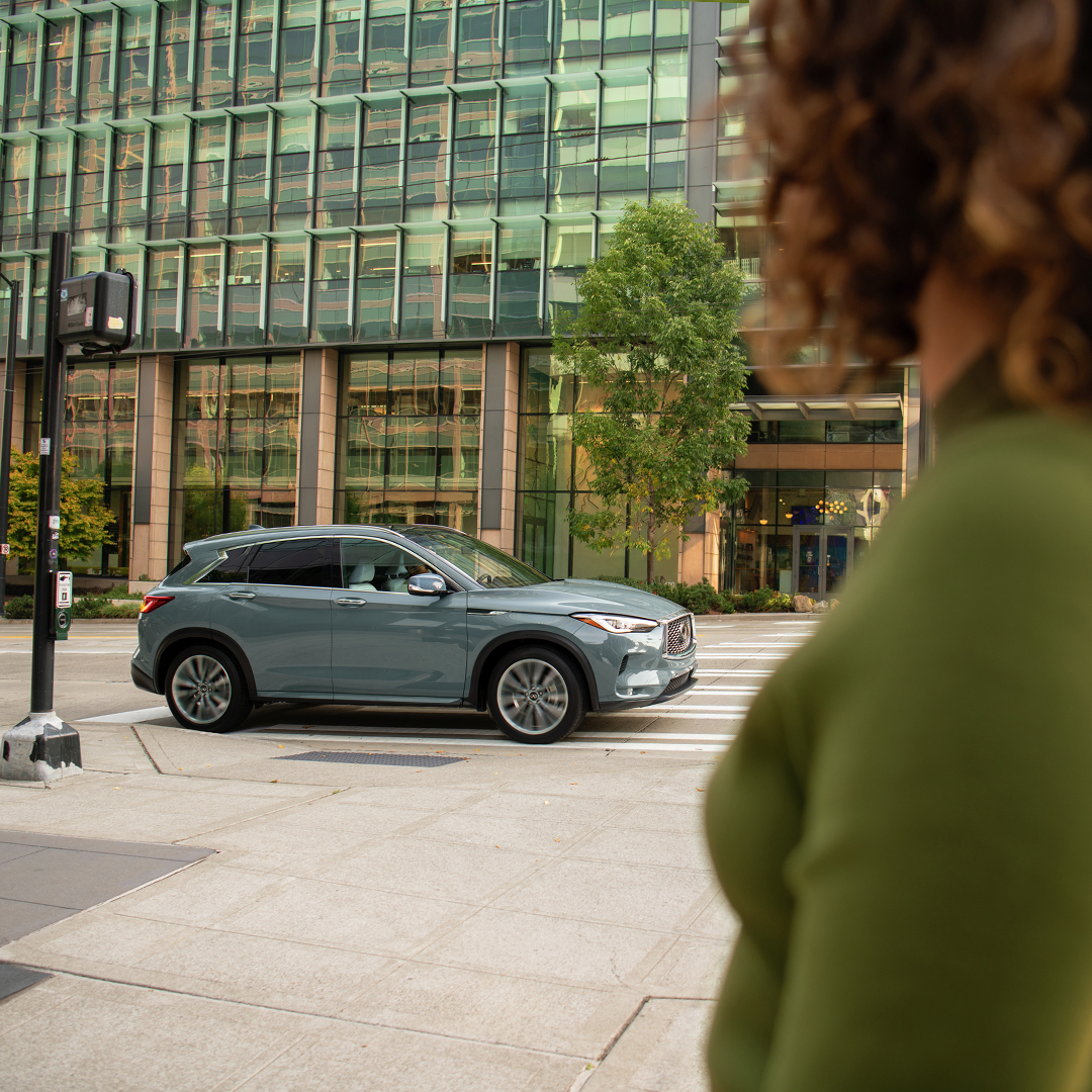 Mujer observando su QX50 estacionado en la calle