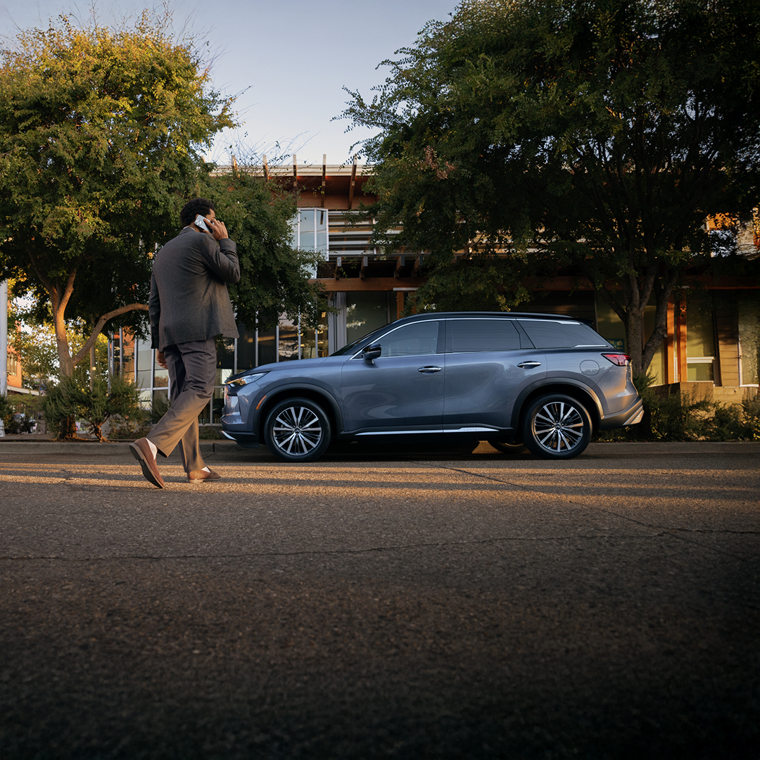 Mujer observando su QX50 estacionado en la calle
